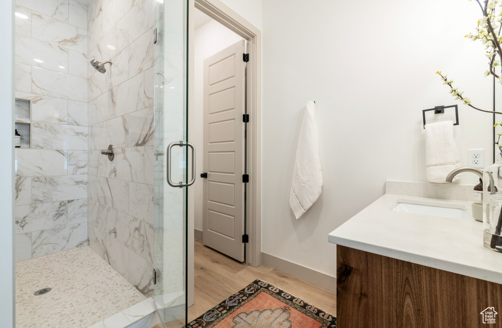 Bathroom featuring vanity, baseboards, wood finished floors, and a stall shower