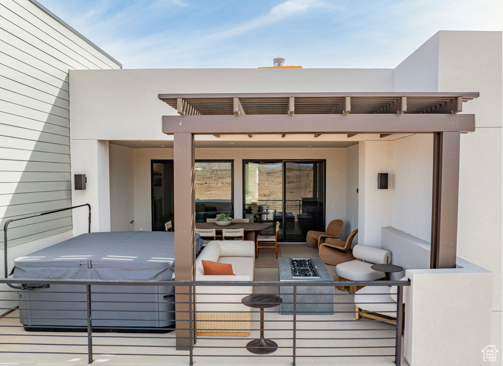 View of patio featuring an outdoor living space with a fire pit, a hot tub, and a balcony
