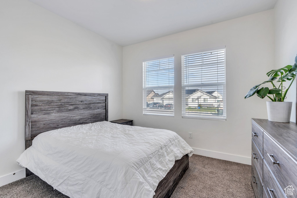 Bedroom with dark carpet, baseboards, and multiple windows