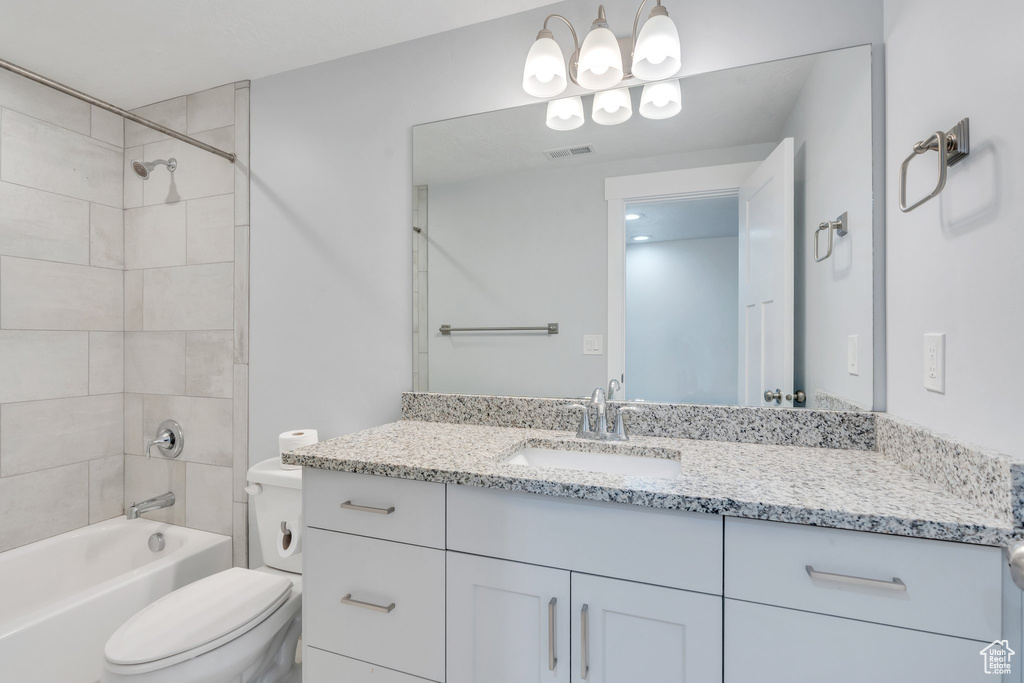 Bathroom featuring a notable chandelier, vanity, toilet, shower / washtub combination, and visible vents