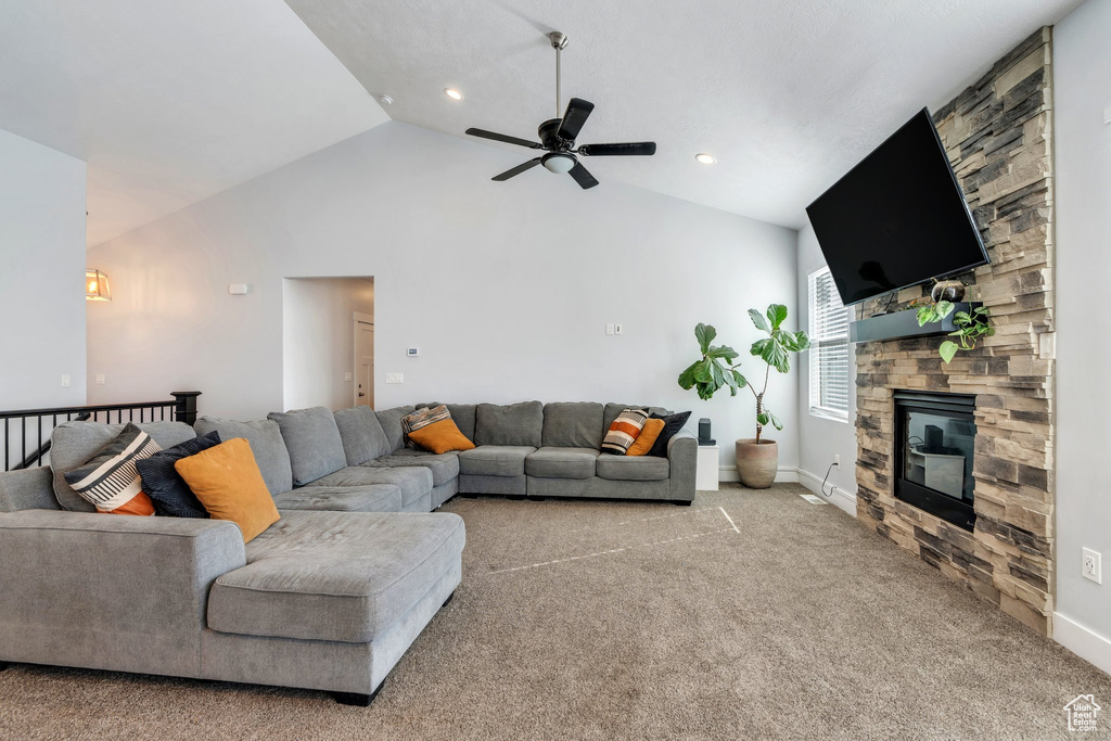 Carpeted living area with ceiling fan, vaulted ceiling, baseboards, and a fireplace