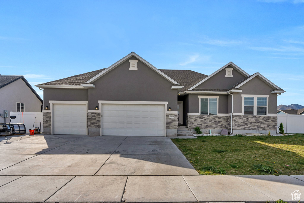 View of front facade featuring fence, a garage, stucco siding, a front yard, and driveway