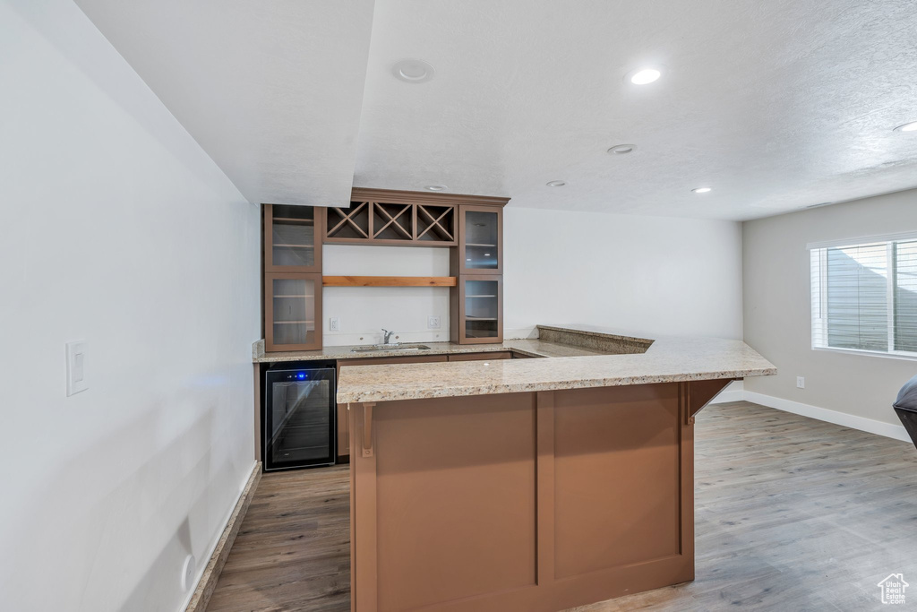 Kitchen with open shelves, wine cooler, wood finished floors, glass insert cabinets, and baseboards