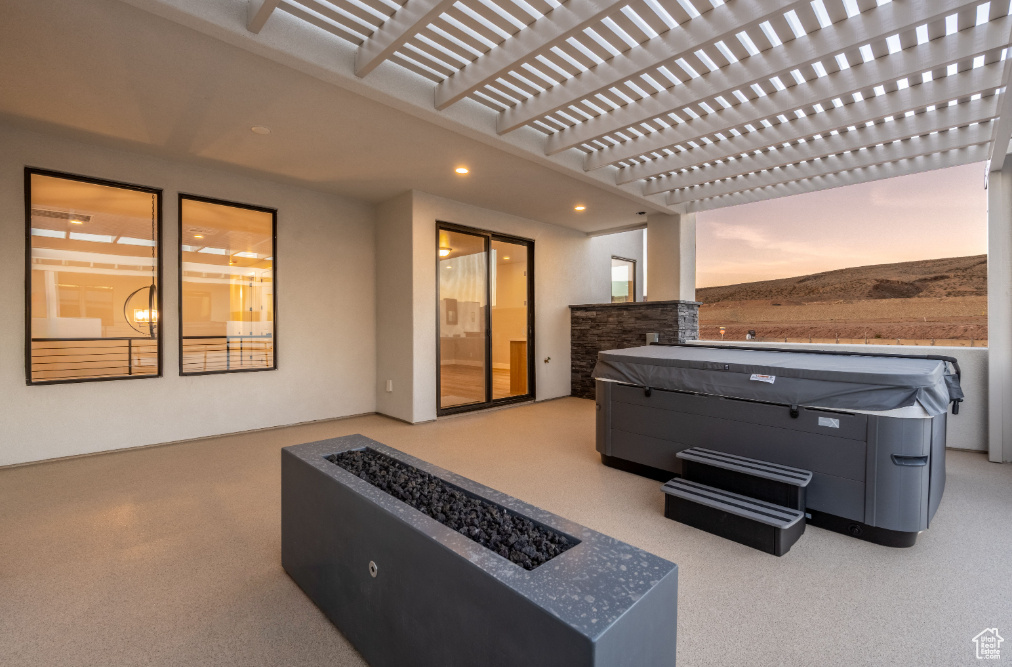 View of patio with a hot tub and an outdoor fire pit