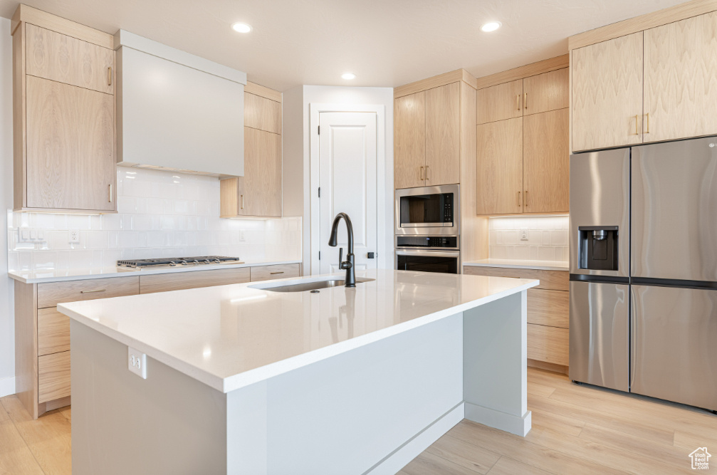 Kitchen featuring a sink, light brown cabinetry, light wood-style floors, and stainless steel appliances