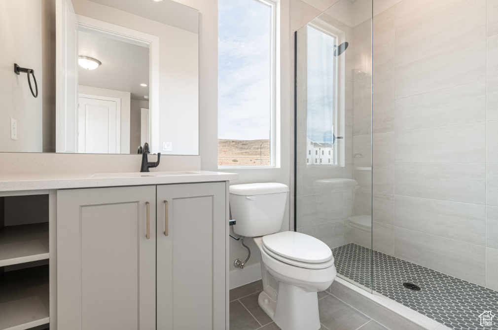 Full bath featuring vanity, tile patterned floors, toilet, and tiled shower