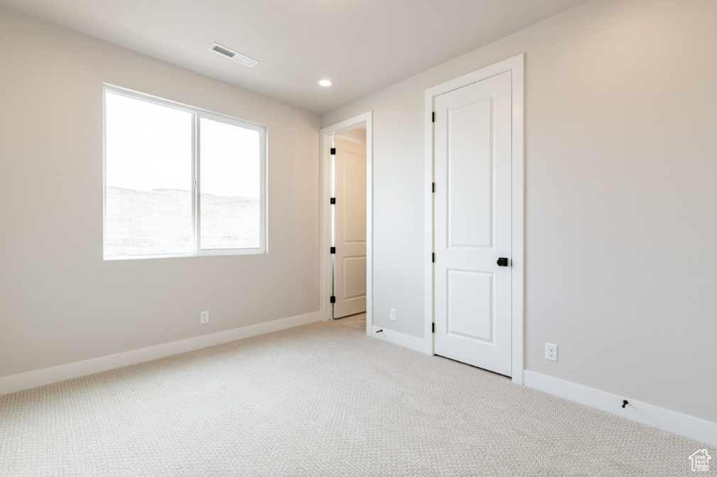Spare room with light colored carpet, baseboards, visible vents, and recessed lighting