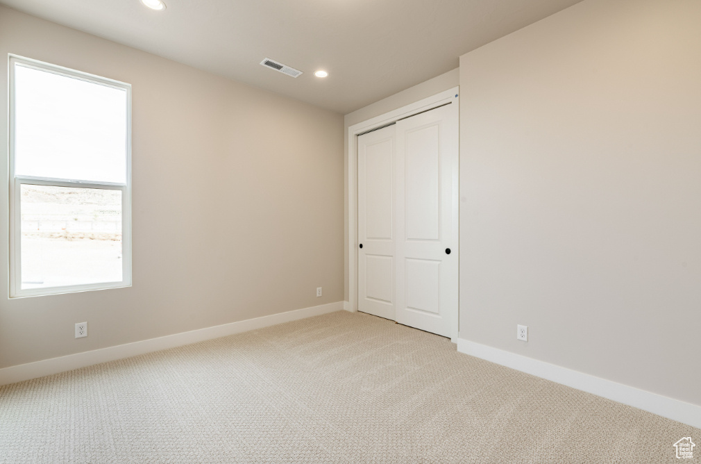 Spare room featuring baseboards, light carpet, recessed lighting, and visible vents