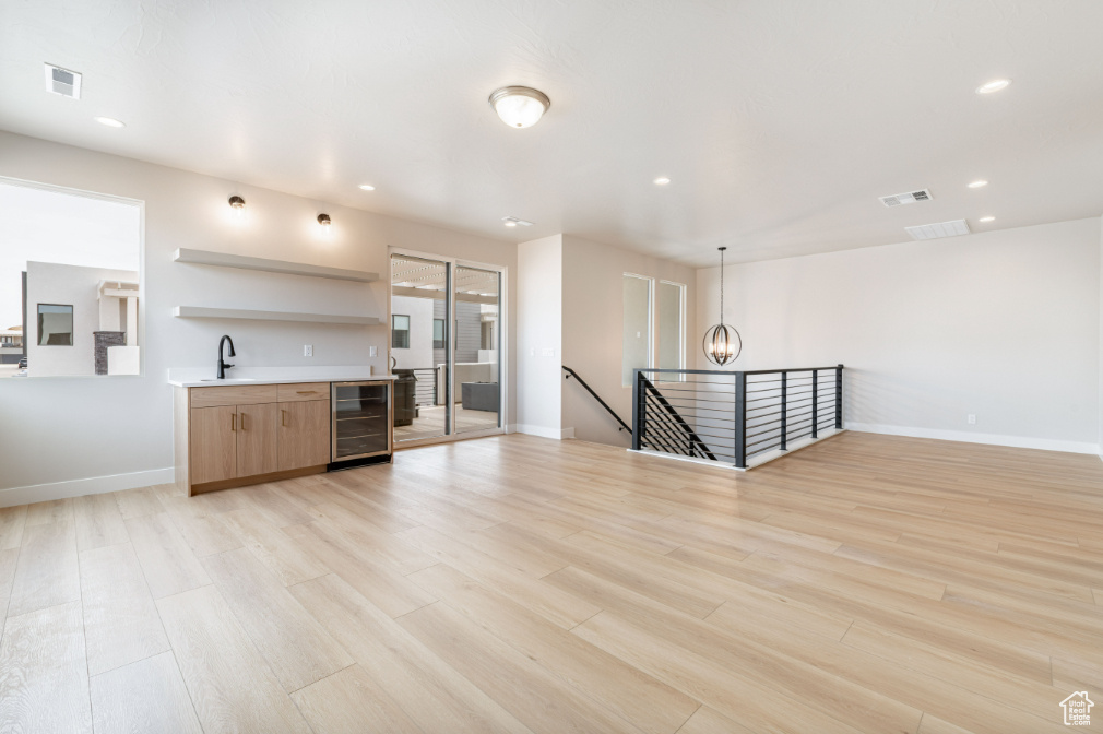 Kitchen featuring open shelves, light wood-type flooring, beverage cooler, and visible vents
