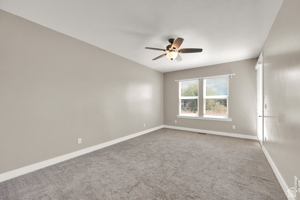 Carpeted empty room with baseboards, ceiling fan, and visible vents