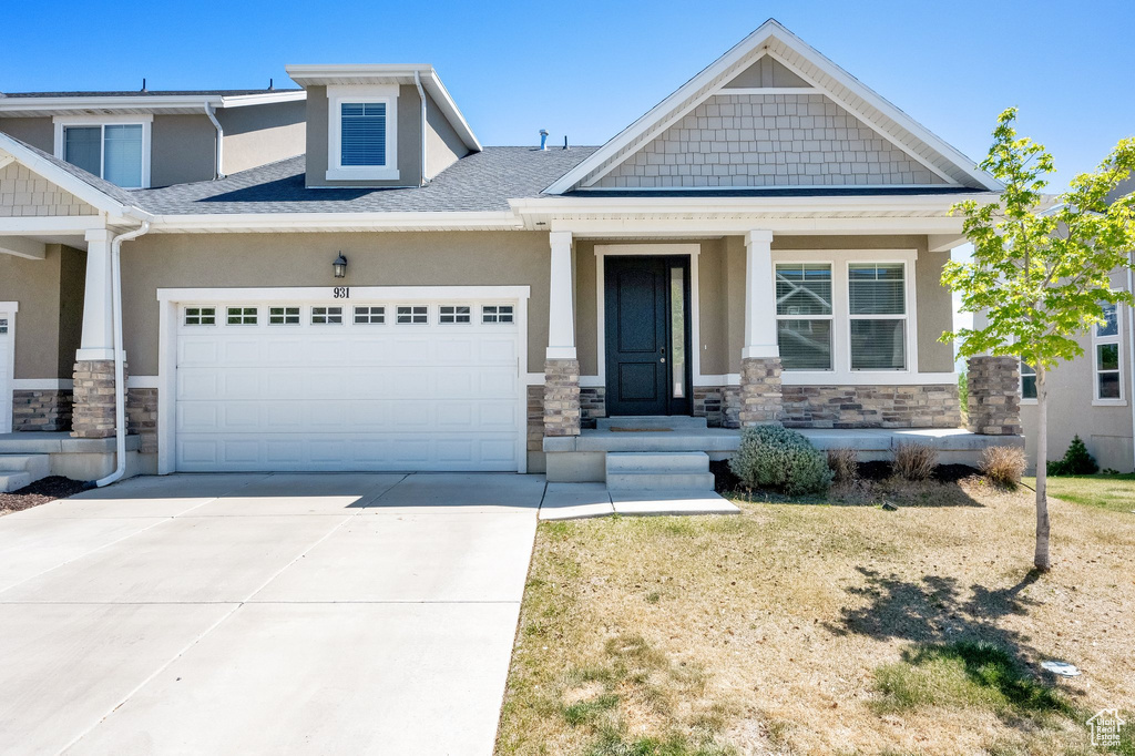 Craftsman-style home with stone siding, a garage, stucco siding, concrete driveway, and covered porch