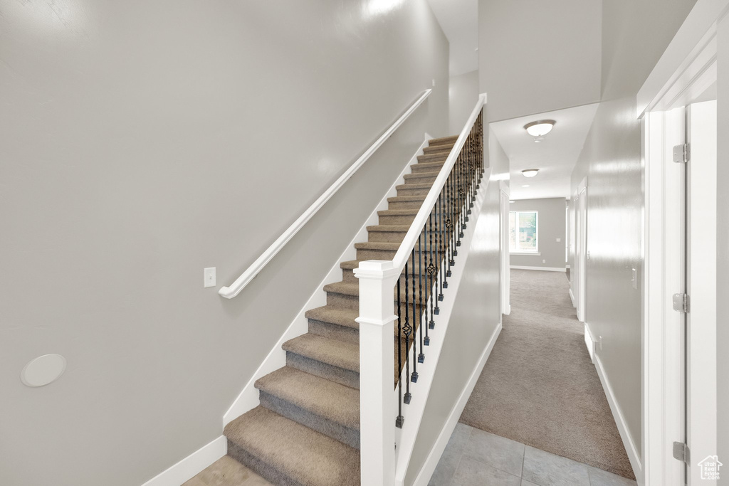 Stairway with carpet flooring, baseboards, and tile patterned floors