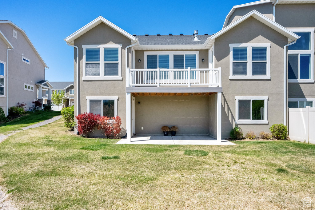 Back of property with a patio, a yard, stucco siding, and a balcony