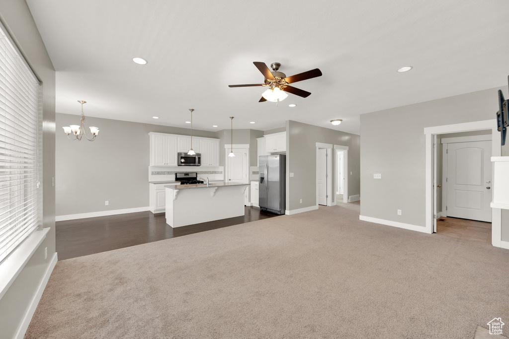 Unfurnished living room featuring recessed lighting, ceiling fan with notable chandelier, and dark carpet