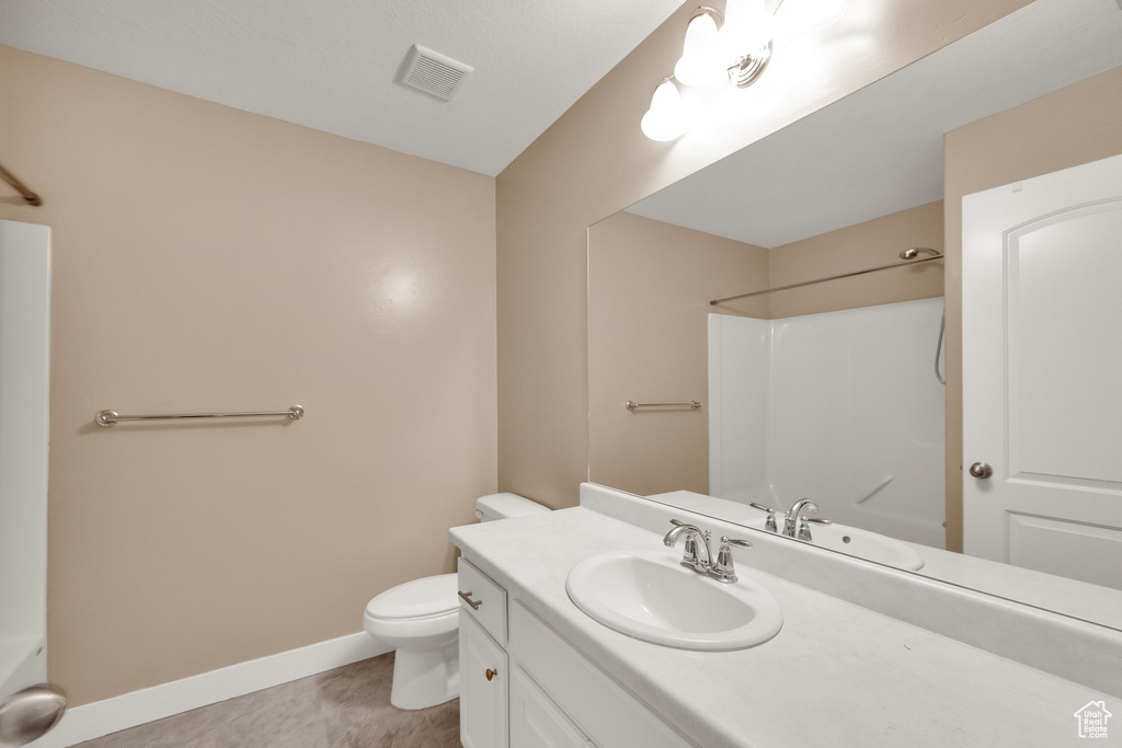 Full bath with visible vents, a shower, vanity, baseboards, and toilet