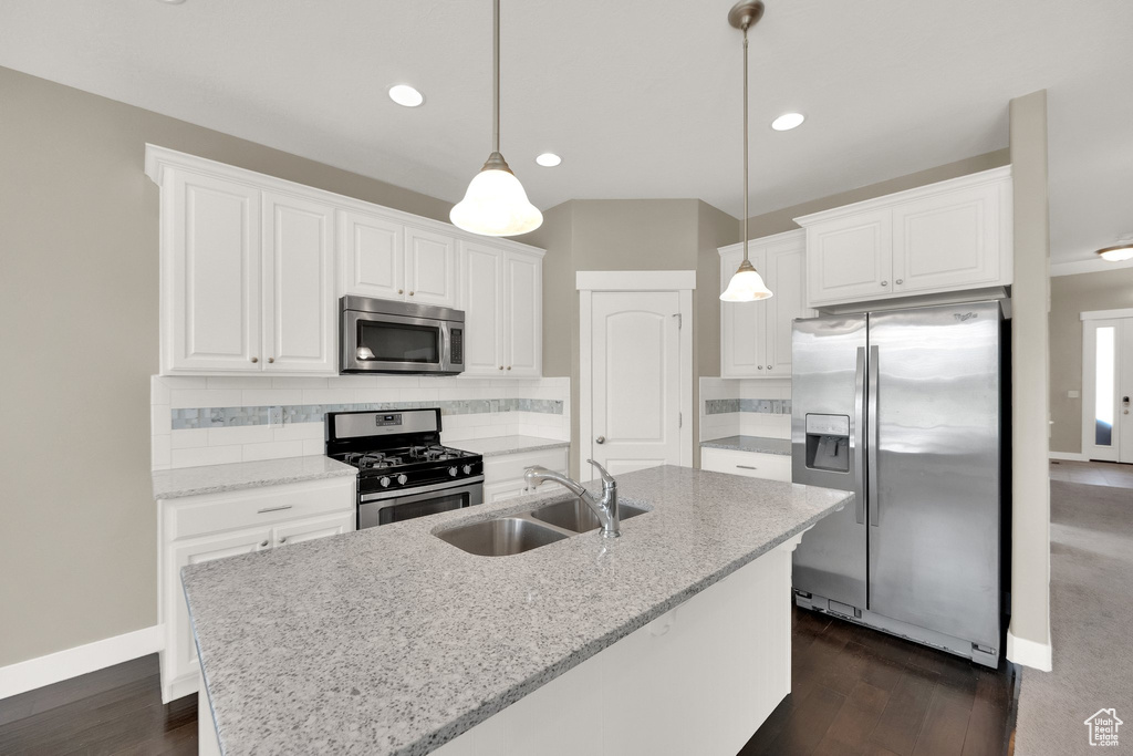 Kitchen with decorative backsplash, white cabinets, a sink, dark wood finished floors, and stainless steel appliances