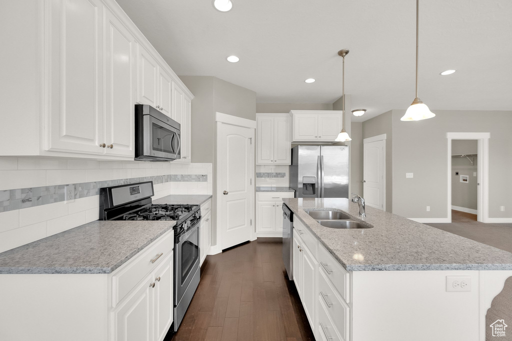 Kitchen featuring white cabinetry, appliances with stainless steel finishes, a sink, and tasteful backsplash