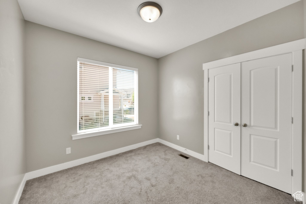 Unfurnished bedroom with baseboards, carpet, a closet, and visible vents
