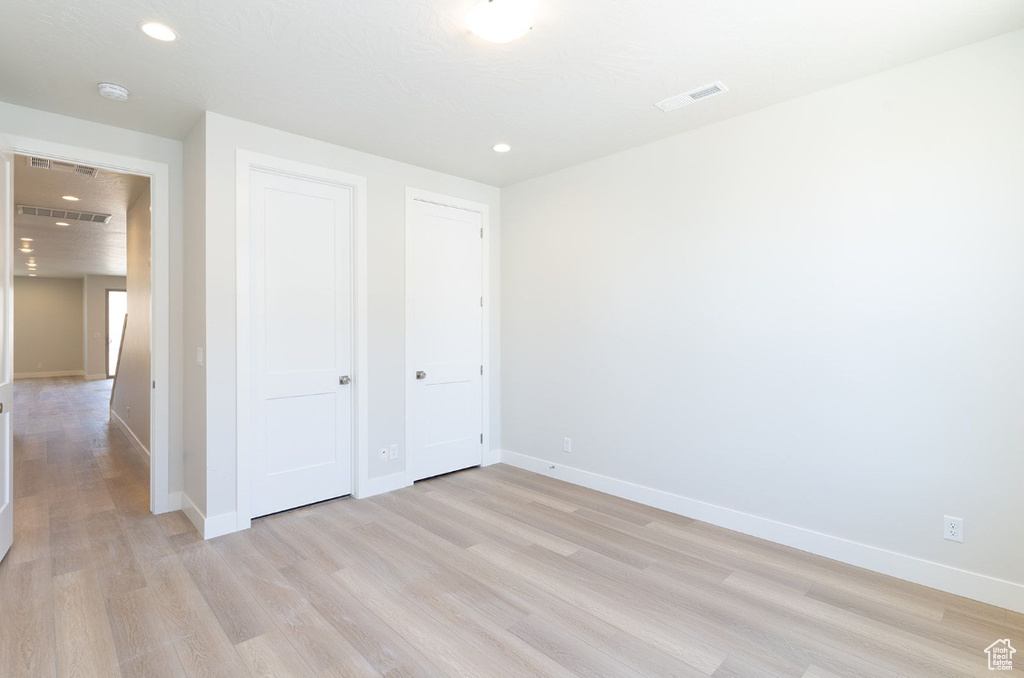 Unfurnished bedroom featuring light wood finished floors, baseboards, recessed lighting, and a closet
