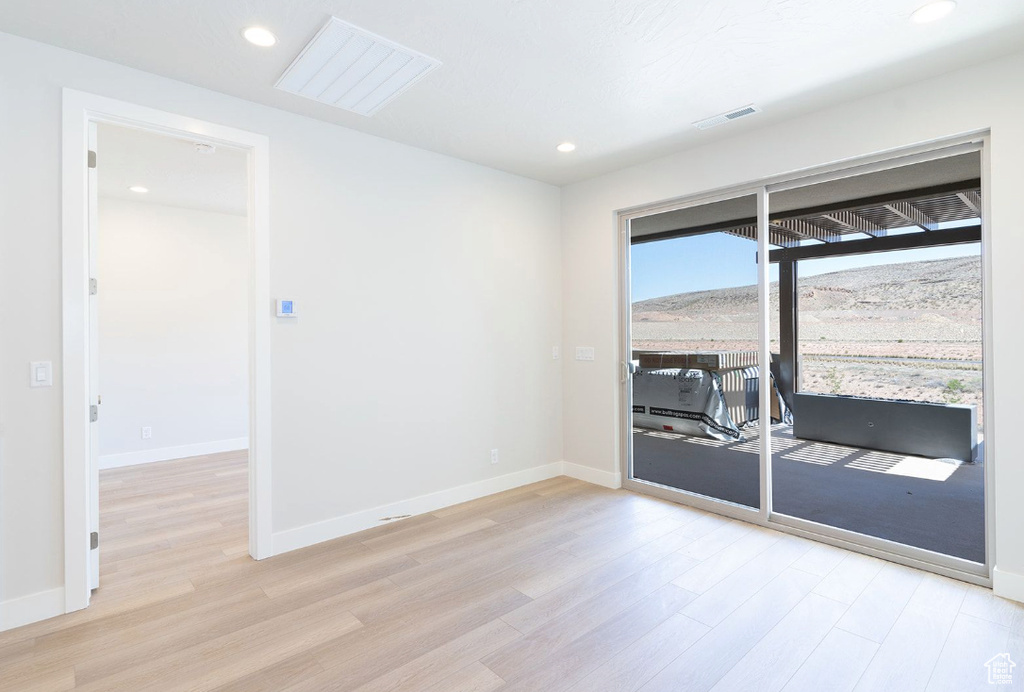 Spare room with baseboards, visible vents, and light wood-style floors