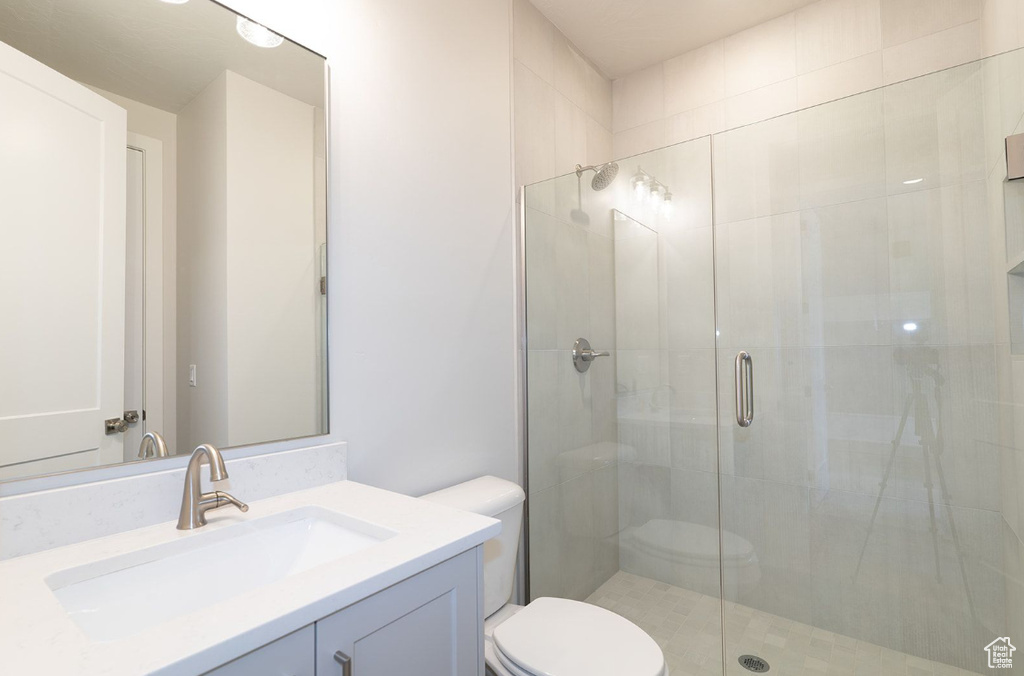 Bathroom with a shower stall, toilet, and vanity