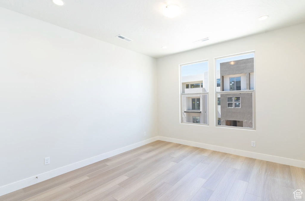 Empty room featuring visible vents, recessed lighting, baseboards, and light wood-type flooring