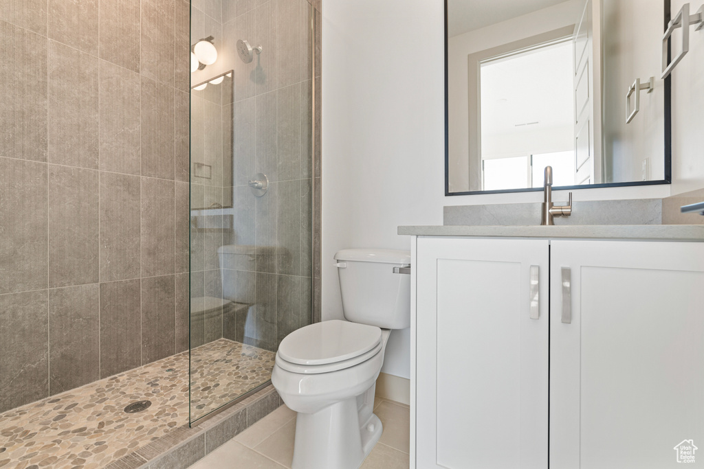 Bathroom with tile patterned flooring, a tile shower, toilet, and vanity