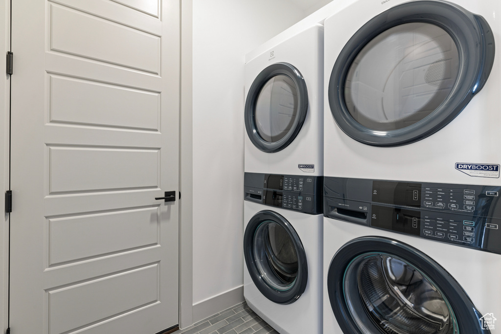 Laundry room with baseboards, laundry area, and stacked washer / dryer