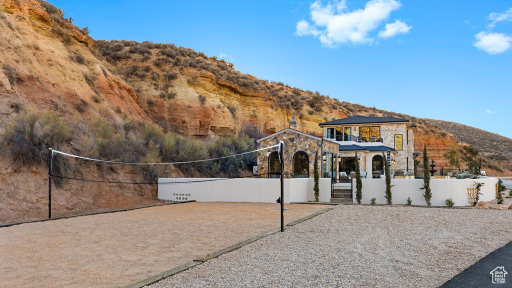 View of front facade featuring fence private yard, a mountain view, volleyball court, and stone siding
