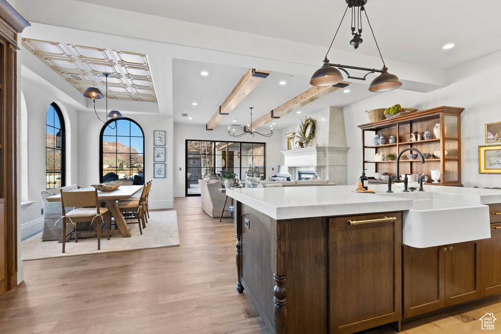 Kitchen with a sink, light countertops, light wood finished floors, open floor plan, and recessed lighting
