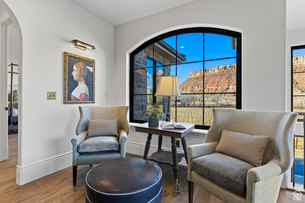 Living area featuring baseboards, arched walkways, and wood finished floors