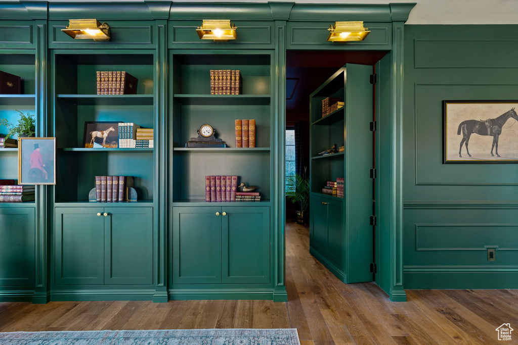 Interior space with wood finished floors, a decorative wall, and built in shelves