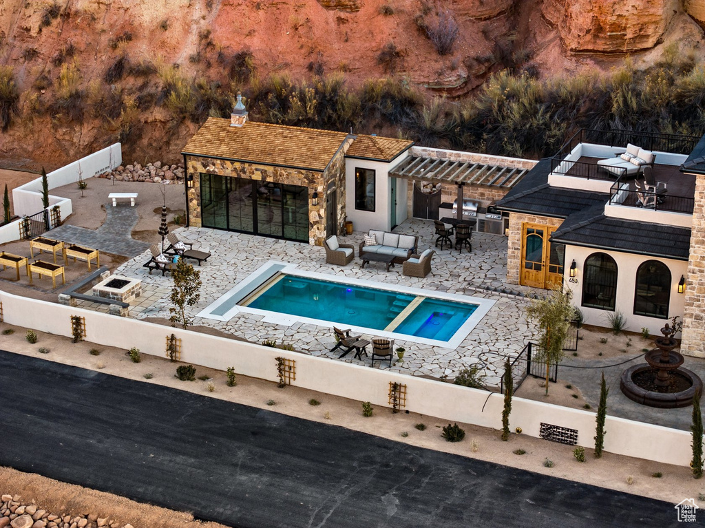 View of pool with an outbuilding, a patio area, fence, a bar, and an outdoor hangout area