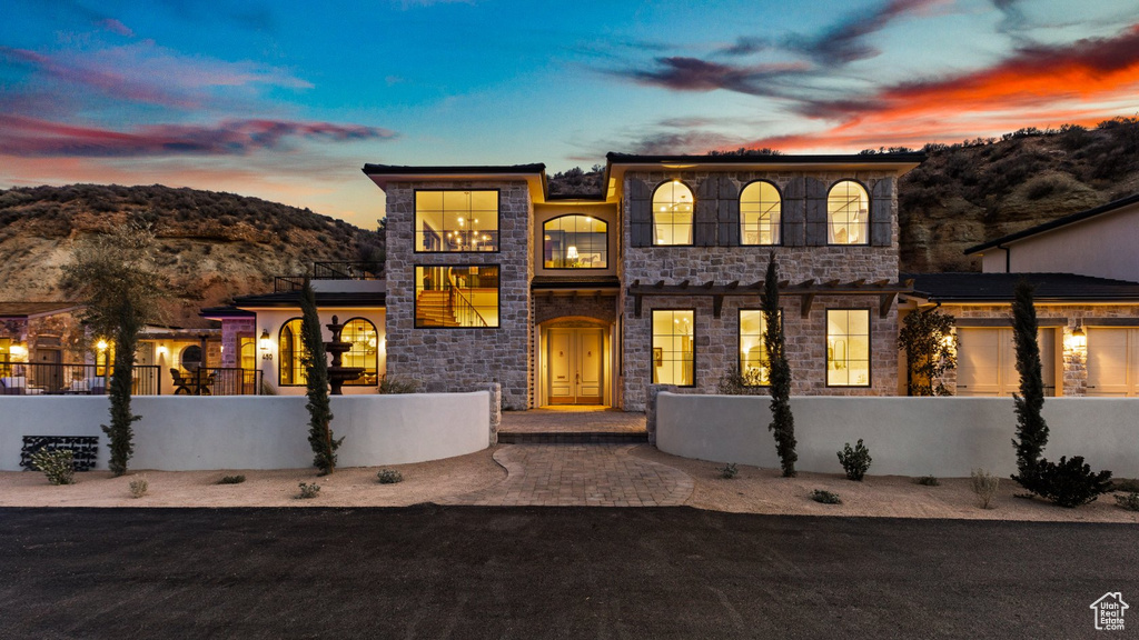 View of front of property featuring a fenced front yard, a mountain view, and stone siding