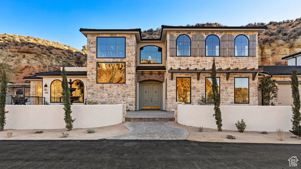 View of front of property with fence, a mountain view, and stone siding