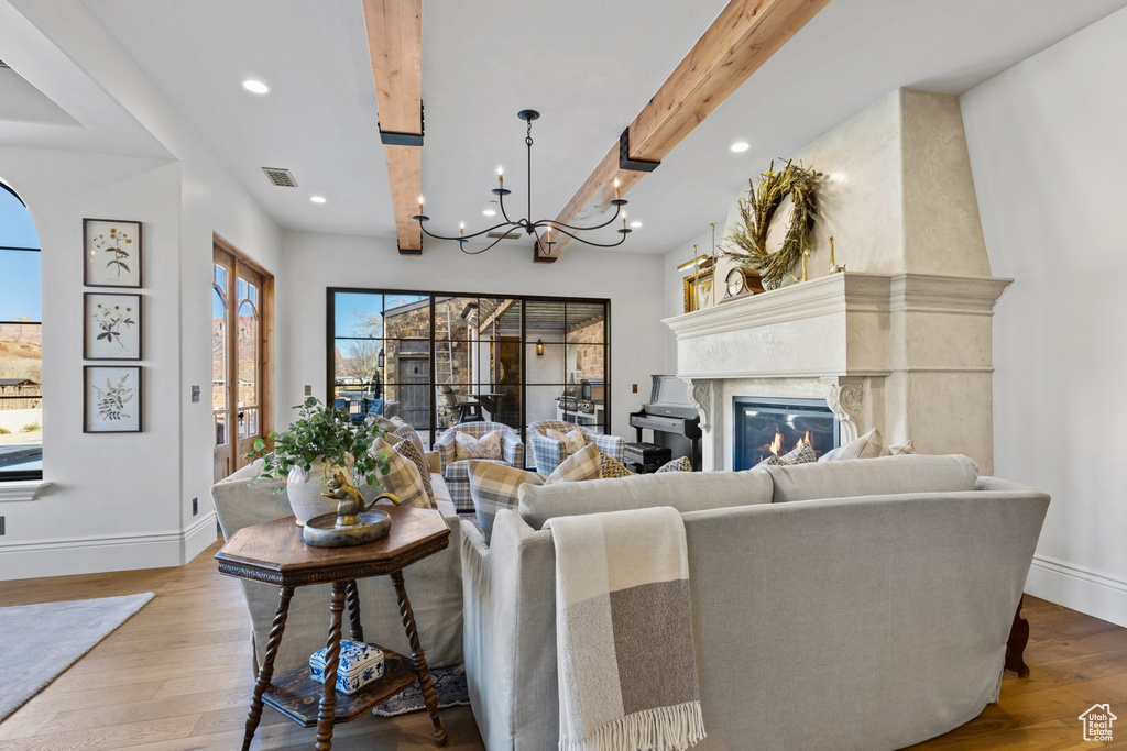 Living room with baseboards, wood finished floors, a notable chandelier, and beam ceiling
