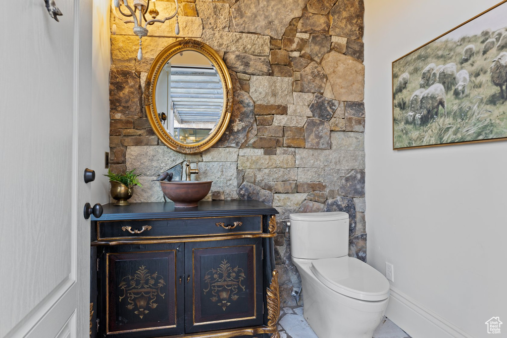 Half bath featuring vanity, baseboards, and toilet