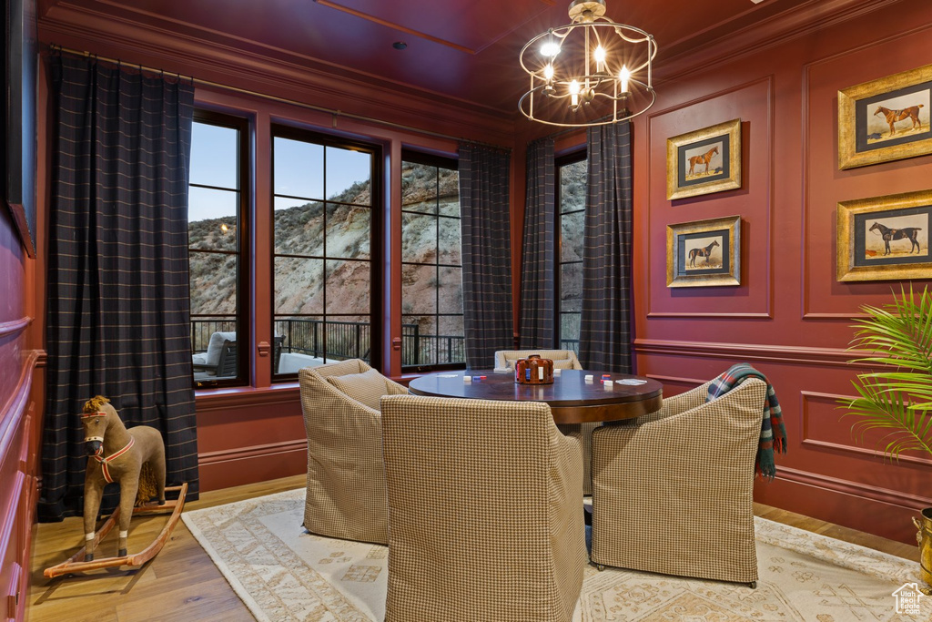 Dining room with a chandelier, ornamental molding, wood finished floors, and a decorative wall