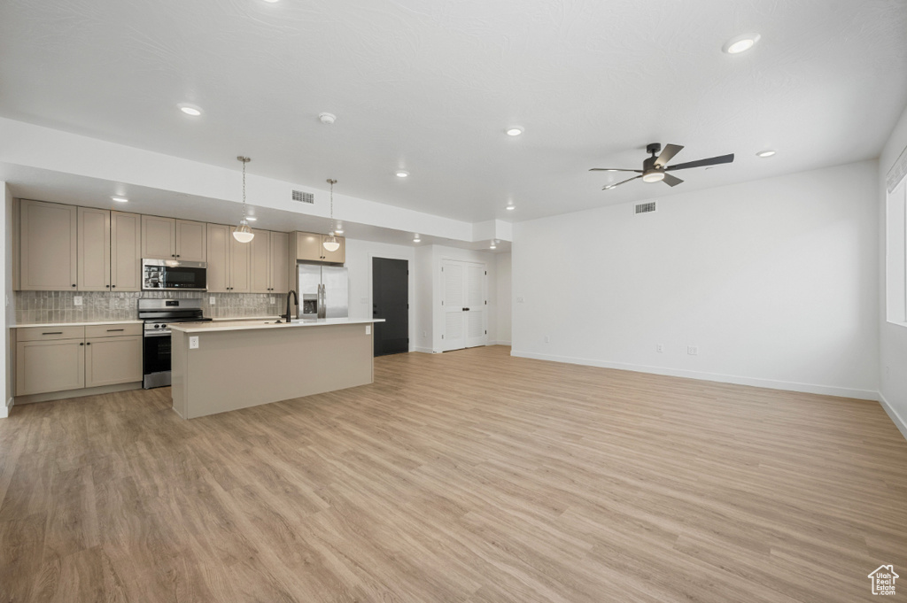 Kitchen featuring decorative backsplash, ceiling fan, light countertops, open floor plan, and stainless steel appliances