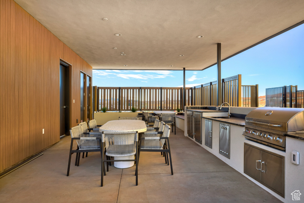 View of patio featuring fence, an outdoor kitchen, area for grilling, outdoor dining area, and a sink
