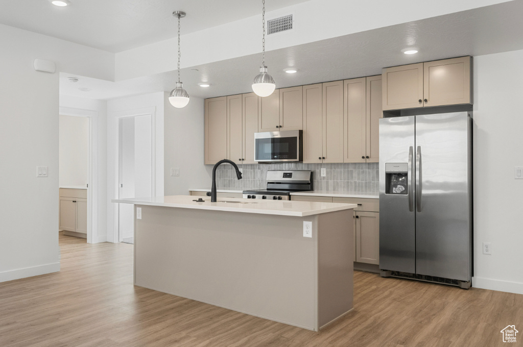 Kitchen with visible vents, light wood-style flooring, appliances with stainless steel finishes, and tasteful backsplash