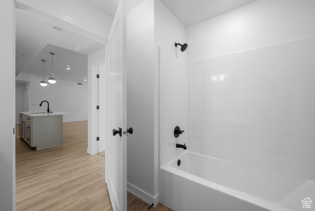 Bathroom with baseboards, shower / bathing tub combination, vanity, and wood finished floors