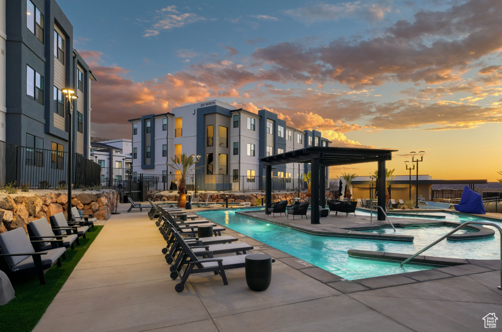 Pool at dusk featuring a community hot tub, a community pool, and a patio