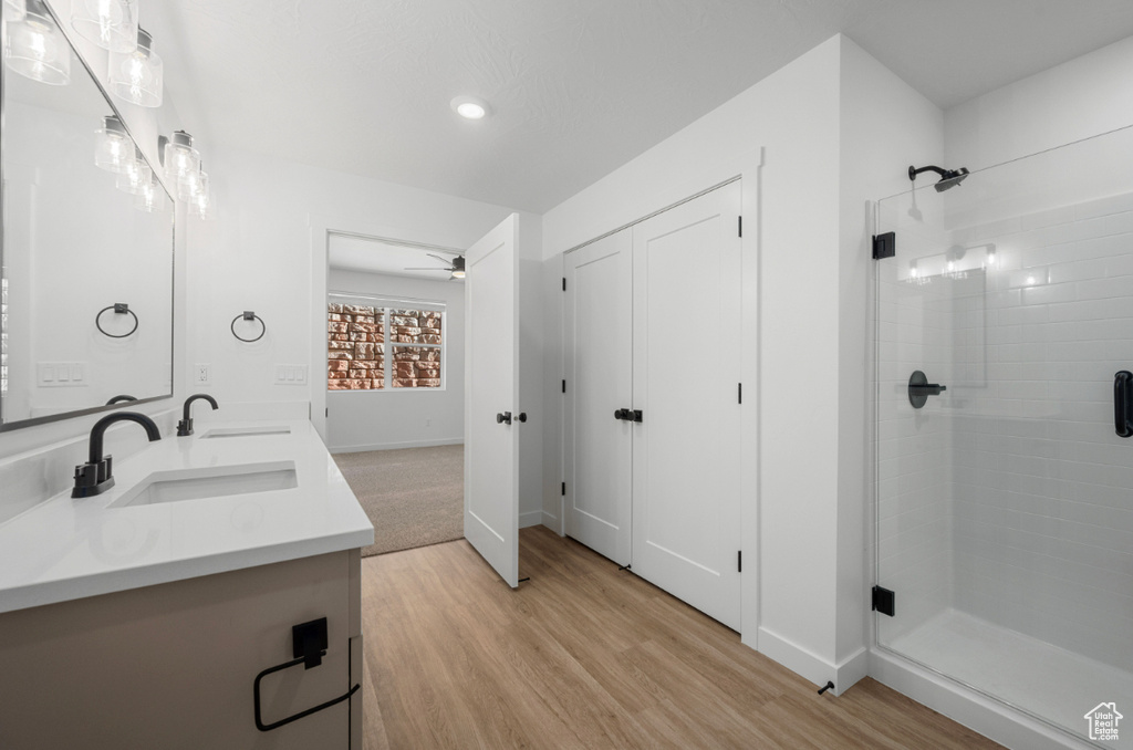 Bathroom with a sink, double vanity, baseboards, wood finished floors, and a stall shower