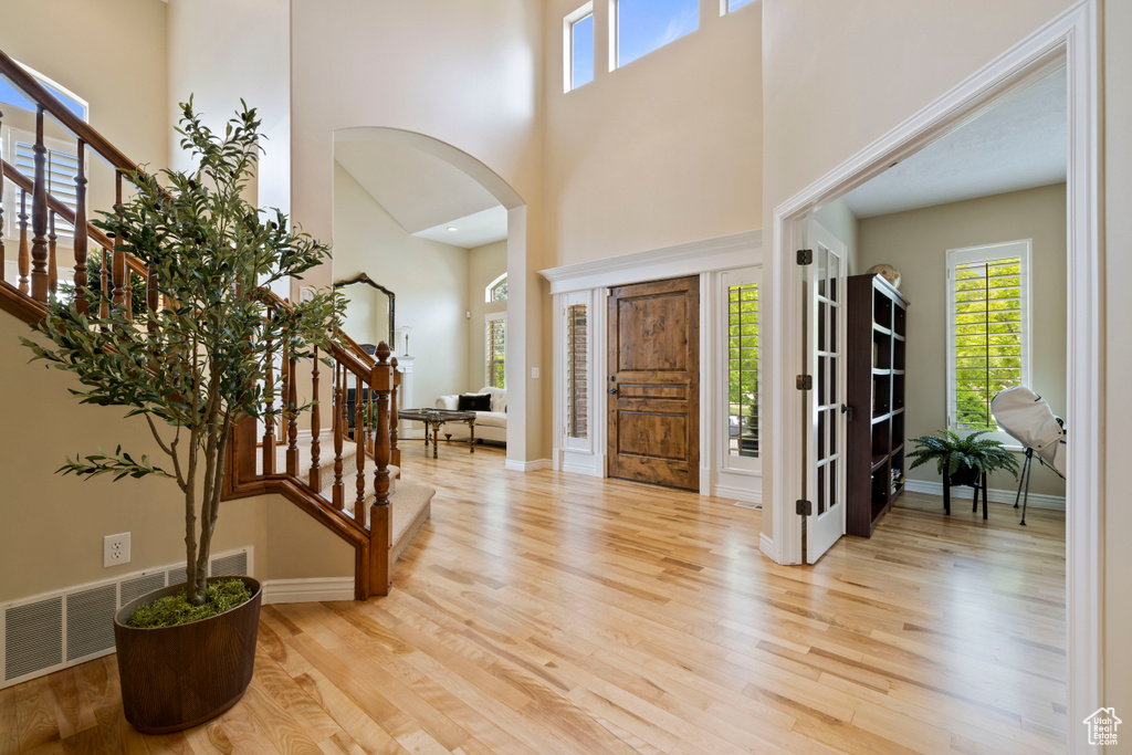 Entryway with plenty of natural light, stairway, wood finished floors, and a towering ceiling
