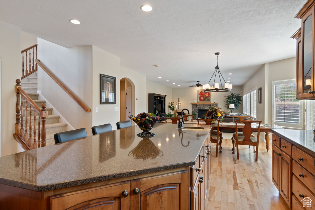 Kitchen with a fireplace, light wood-style floors, open floor plan, recessed lighting, and a sink