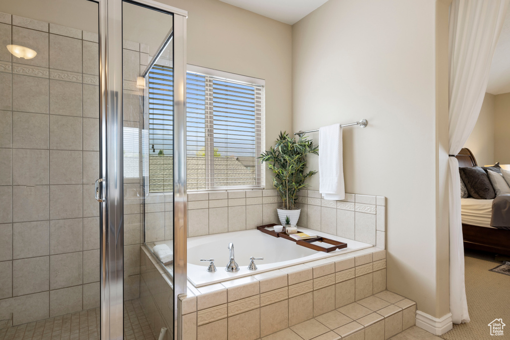 Ensuite bathroom with a stall shower, connected bathroom, a garden tub, and baseboards