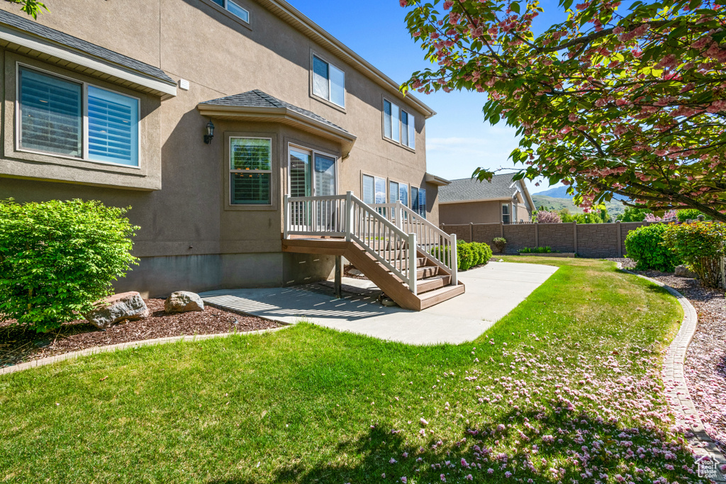 Back of property with stucco siding, a patio area, fence, and a lawn