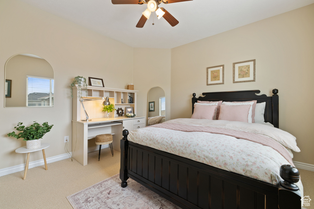 Bedroom featuring ceiling fan, light carpet, baseboards, and arched walkways