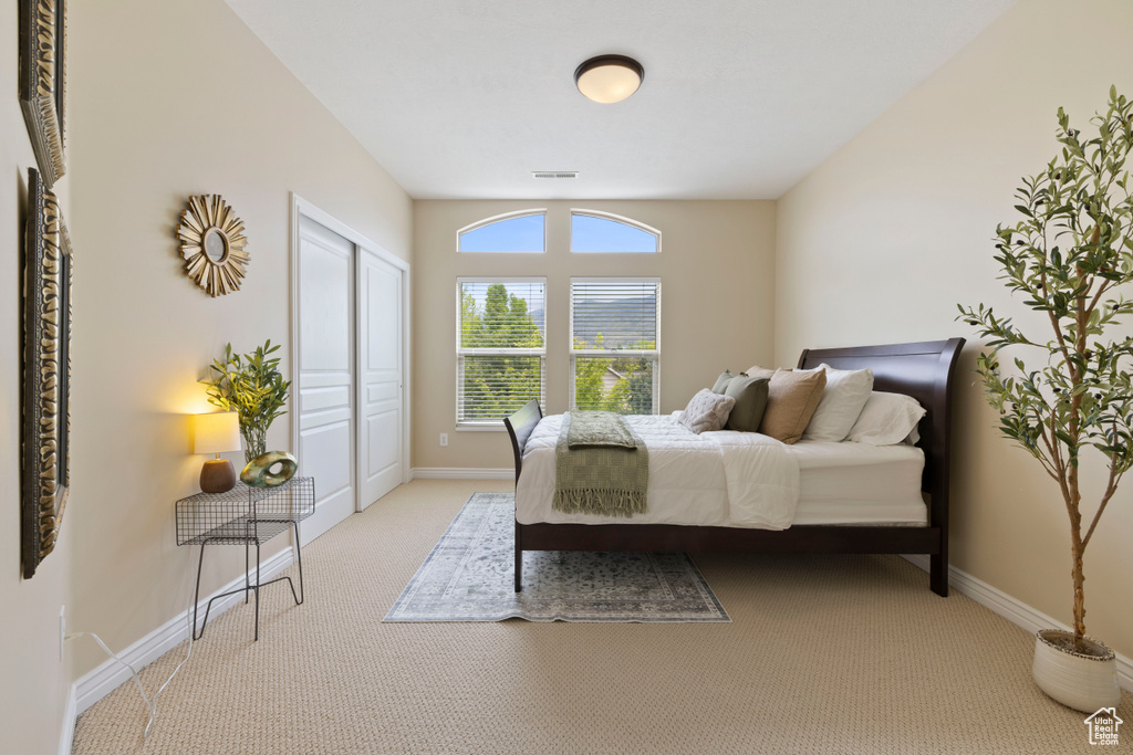 Bedroom with baseboards, a closet, visible vents, and light colored carpet